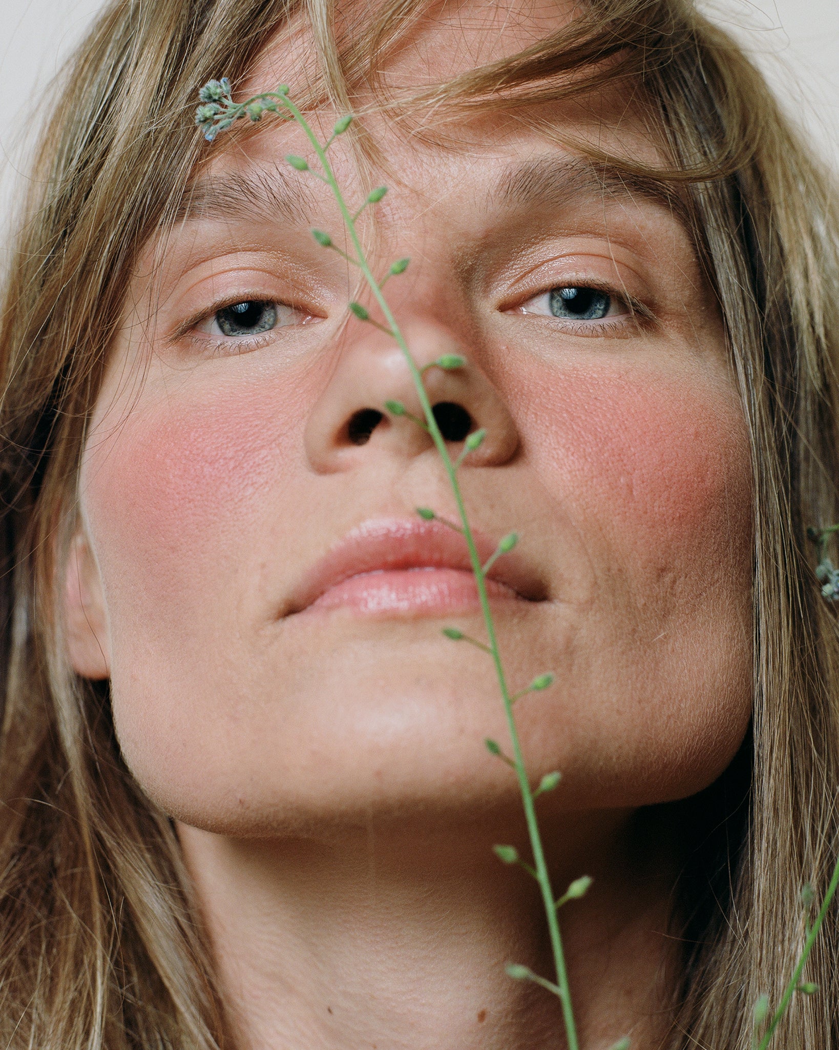 Model wearing MÁDARA Organic Skincare mineral cheek blush bare blossom on A6822 on skin; close-up portrait shows natural application results.