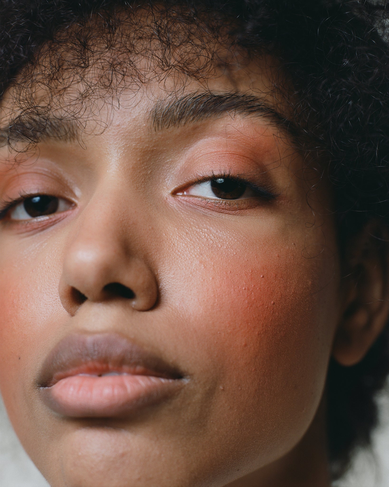 Model wearing MÁDARA Organic Skincare magnetic blush fierce flame on A6821 on skin; close-up portrait shows natural application results.